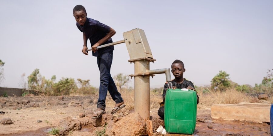 Dos niños usando una bomba de agua en África